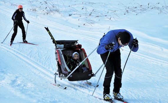 Aikuinen vetää hiihtäen lasta perässään